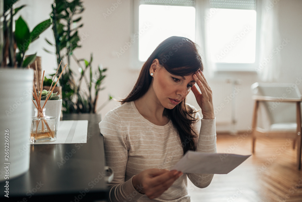 Φωτογραφία Portrait of a worried woman looking at received letter at home.
