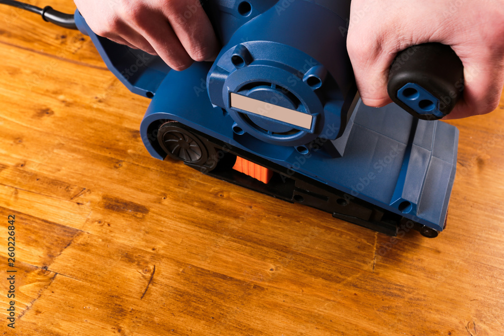 Fototapeta premium sandar tool with mans hands on wooden background