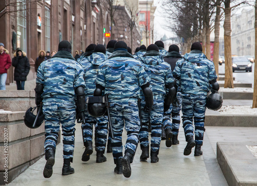 Russian OMON police in protective gear and helmets in their hands walking down the street. Strong men. photo