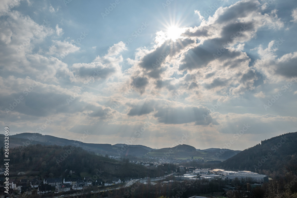 Dramatischer Himmel mit Sonne über ländlichem Industriegebiet 
