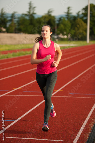 Beautiful young woman runner run on a track in early summer afternoon © Samo Trebizan