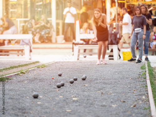Girls playing petanque against retro style cafe on a sunset