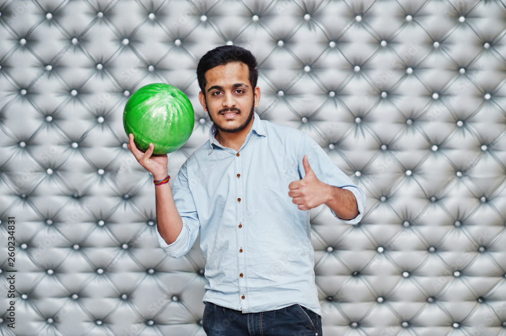 Stylish asian man in jeans shirt standing with bowling ball at