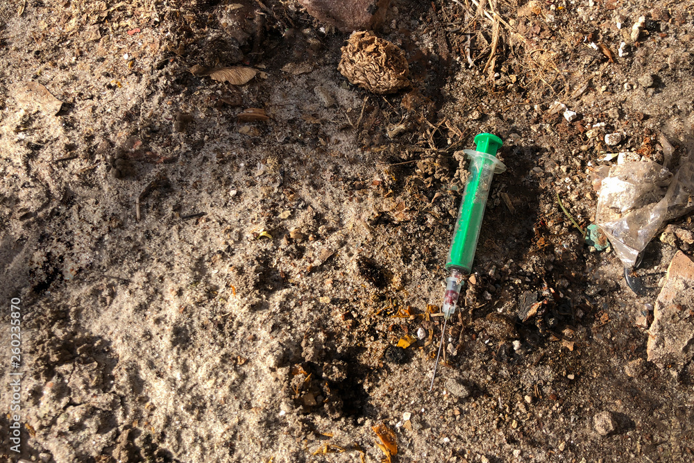 Dangerous infected syringe for injection dropped on the ground, view