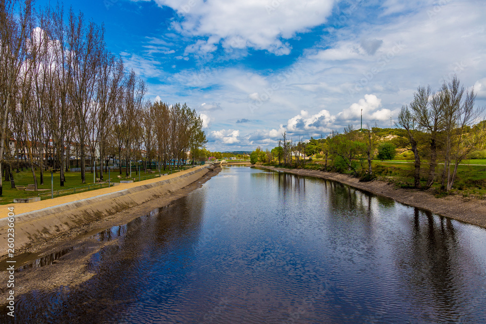 Fototapeta premium River Scene Beside a Public Park Under a Blue Sky
