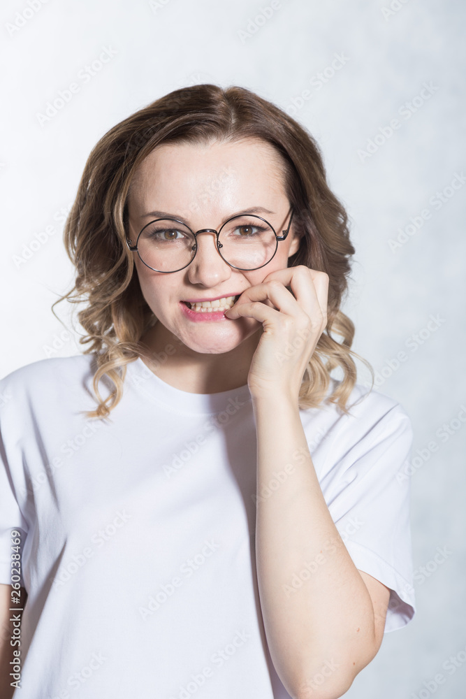 Beautiful young woman feels anxious, bites finger nails in confusion. Beautiful young woman feels anxious, bites finger nails in confusion.