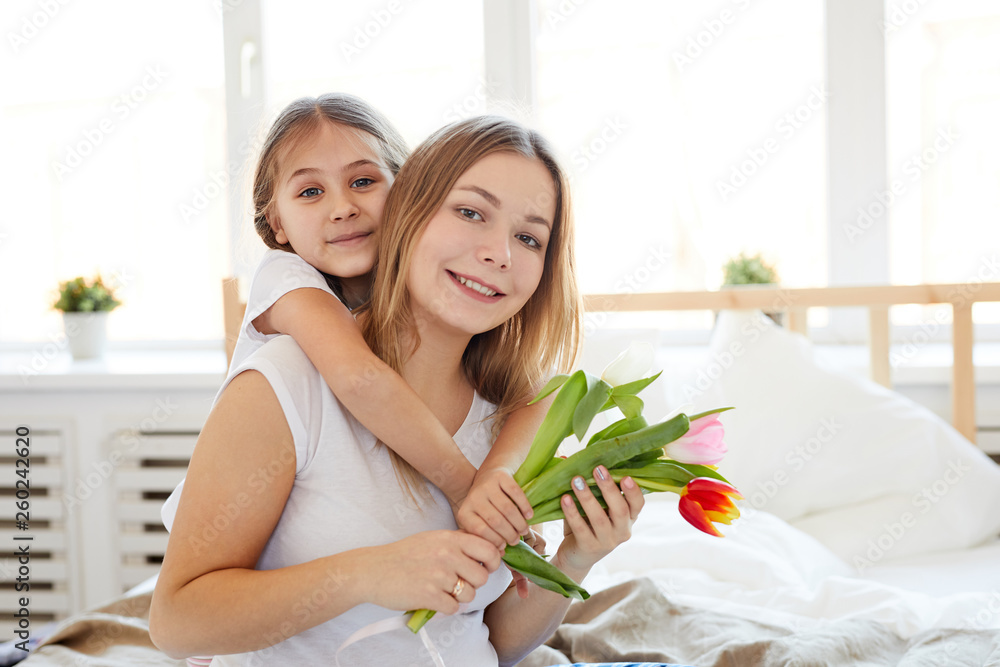 Waist up portrait of cute little girl embracing mother on Mothers day, both posing looking at camera, copy space Waist up portrait of cute little girl embracing mother on Mothers day, both posing looking at camera, copy space