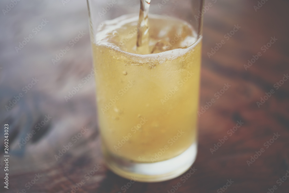 Pouring beer water in to glass with ice and froth Pouring beer water in to glass with ice and froth
