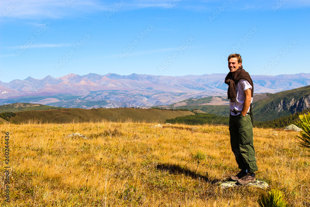 Tourist posing for photos on the background of the autumn landscape of the Altai mountains Tourist posing for photos on the background of the autumn landscape of the Altai mountains