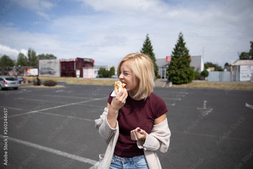 Young beautiful girl eating hot dog in the parking lot. Young beautiful girl eating hot dog in the parking lot.
