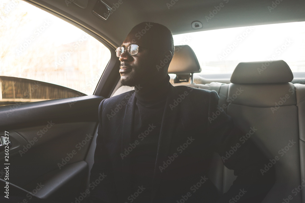 Young business man in the back seat in an expensive car goes to a meeting.