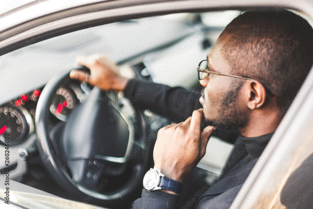 A young businessman in a suit sits at the wheel of a expensive car. A young businessman in a suit sits at the wheel of a expensive car.