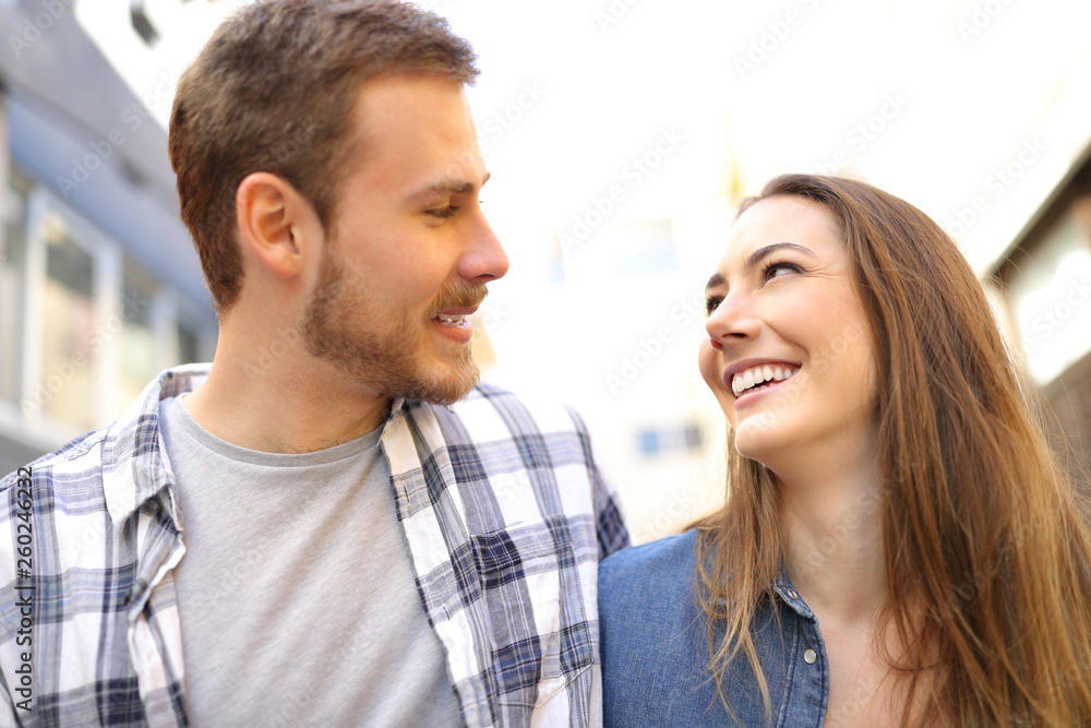 Couple walking looking each other in love in the street Couple walking looking each other in love in the street