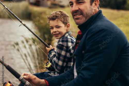 Close up of father and son fishing near a lake
