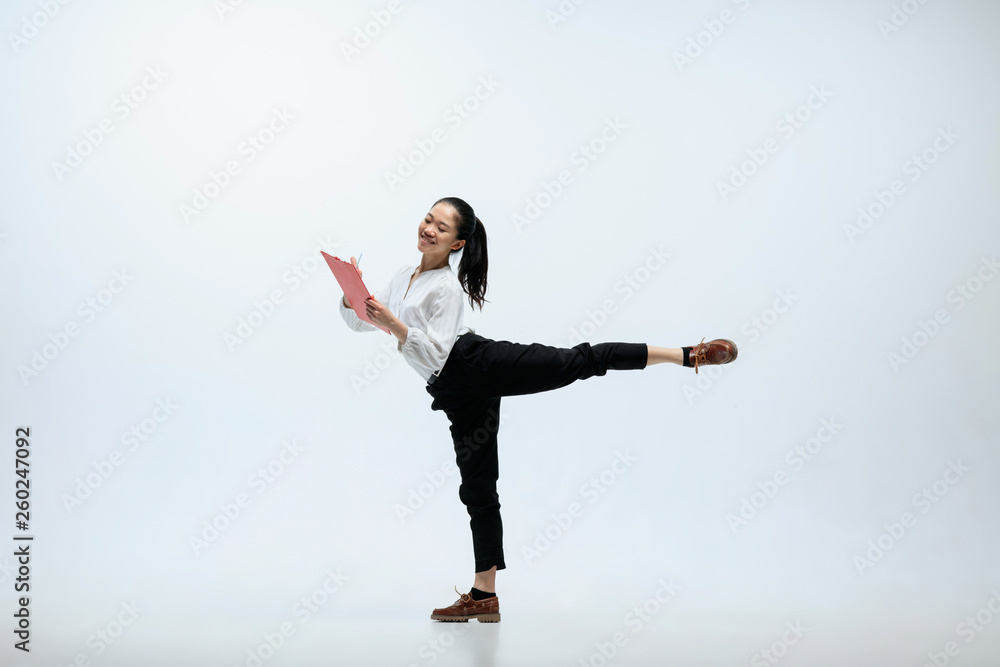 Easy way to be the happiest. Happy woman working at office, jumping and dancing in casual clothes or suit isolated on white studio background. Business, start-up, working open-space concept.