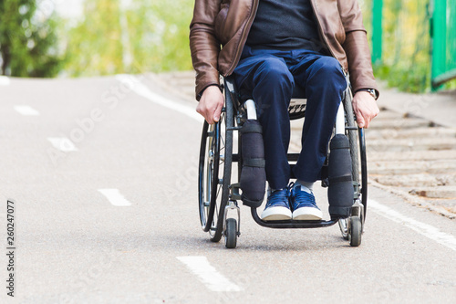 A young man in a wheelchair rides along the park road.