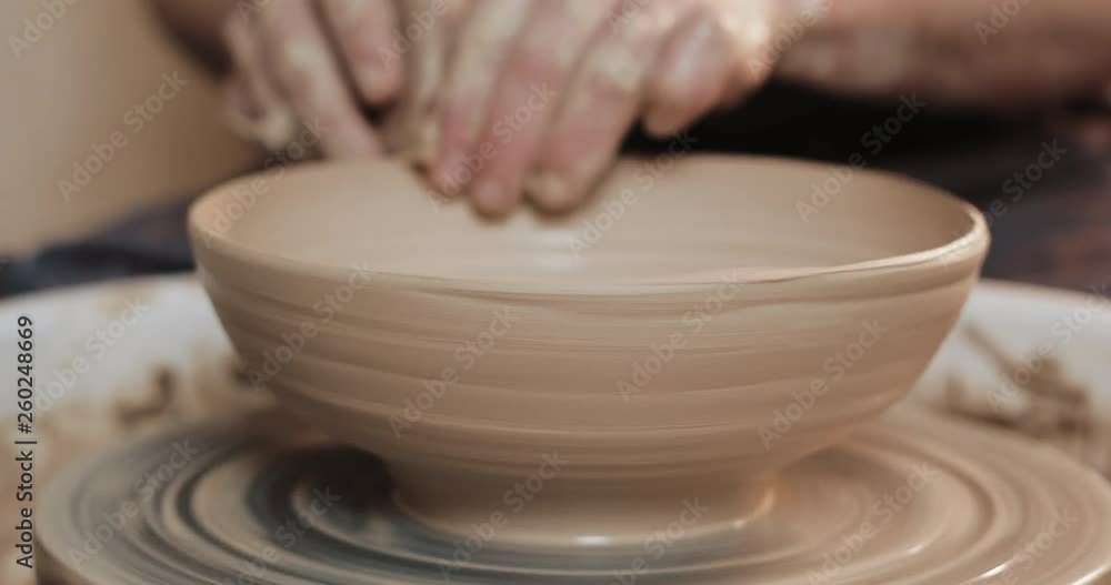Potter in the potter's wheel makes ceramic product using his hands and pottery tools. Close up. Handmade, craft. White clay Potter in the potter's wheel makes ceramic product using his hands and pottery tools. Close up. Handmade, craft. White clay