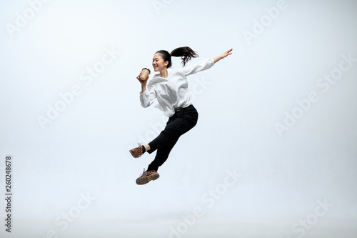 Wallpaper Mural Hurry up to get your coffee. Happy woman working at office, jumping and dancing in casual clothes or suit isolated on white studio background. Business, start-up, working open-space concept. Torontodigital.ca