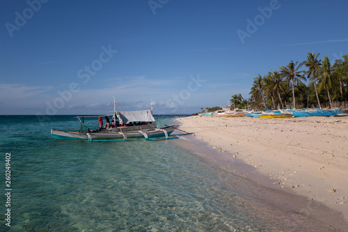 Ferryboat outrigger transportation on a white beach of a little island in countryside rural tranquil scene © photo-vista.de