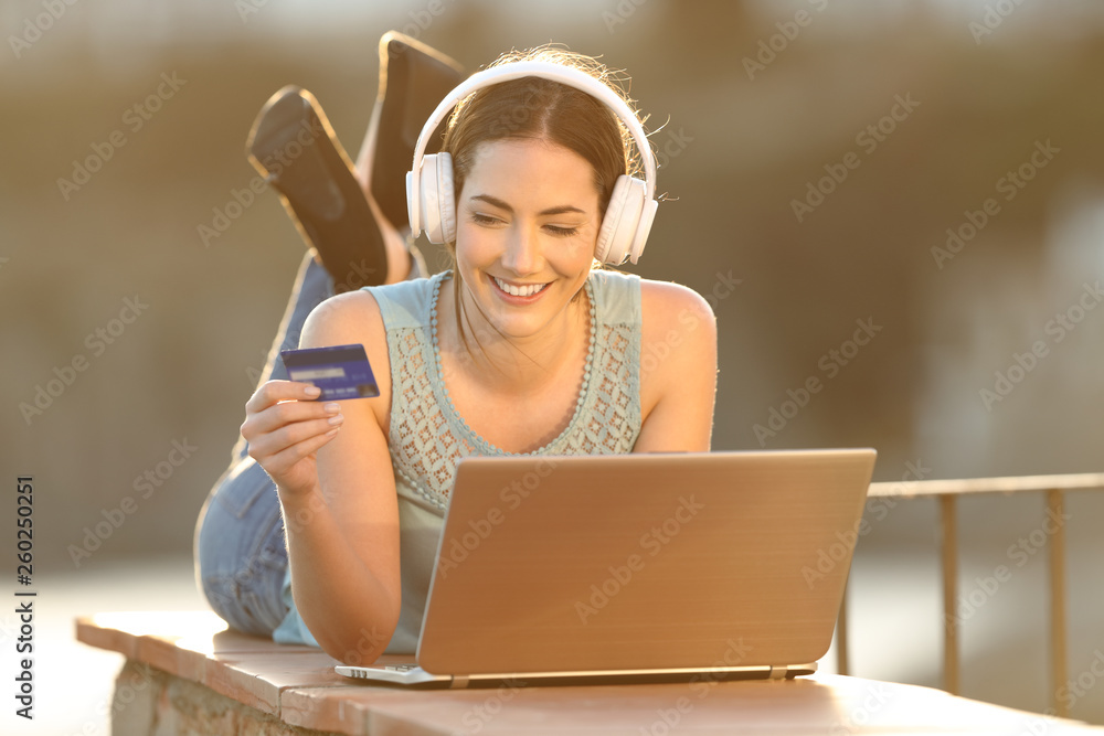 Φωτογραφία Happy woman uses credit card to buy online music or media