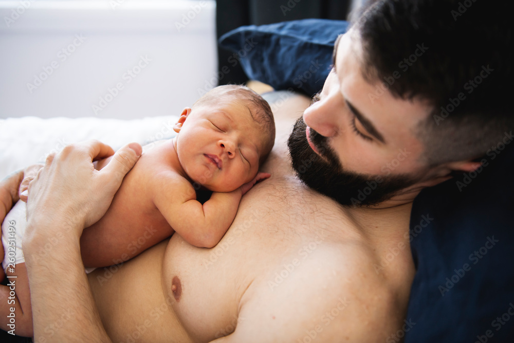 father lay on bed with his newborn baby daughter father lay on bed with his newborn baby daughter