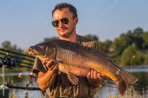 Fototapeta Naklejka Na Ścianę i Meble -  Happy angler with carp fishing trophy