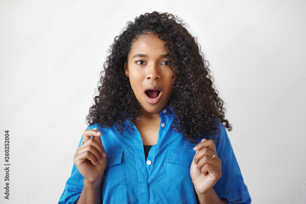 I can't believe it. Casually dressed young Afro American woman employee with curly hairdo keeping mouth wide opened, demonstrating true reaction, surprised with unexpected promotion at work I can't believe it. Casually dressed young Afro American woman employee with curly hairdo keeping mouth wide opened, demonstrating true reaction, surprised with unexpected promotion at work