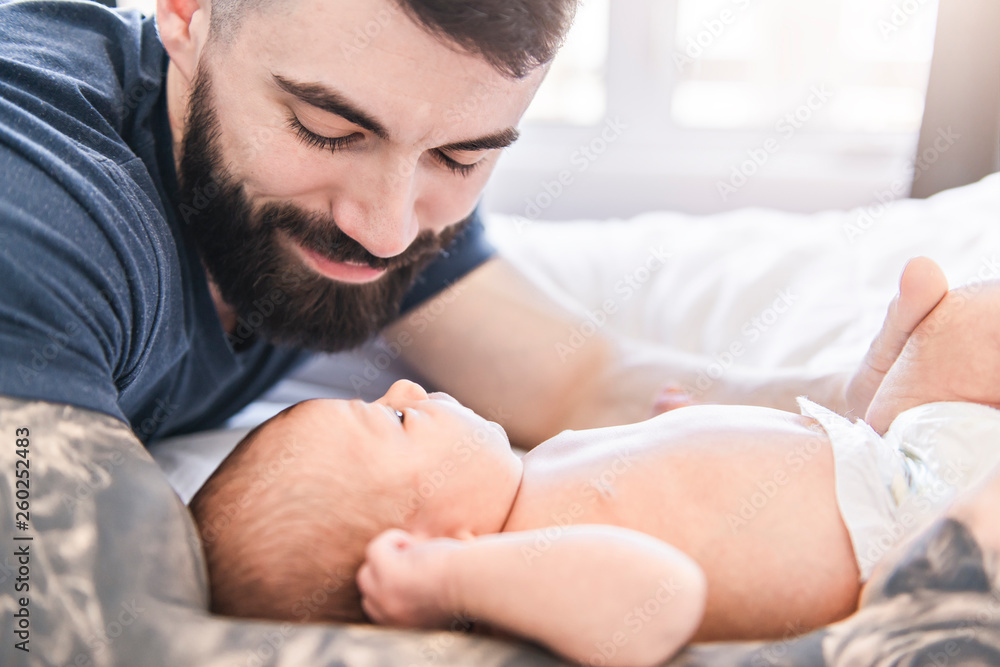 father lay on bed with his newborn baby daughter father lay on bed with his newborn baby daughter