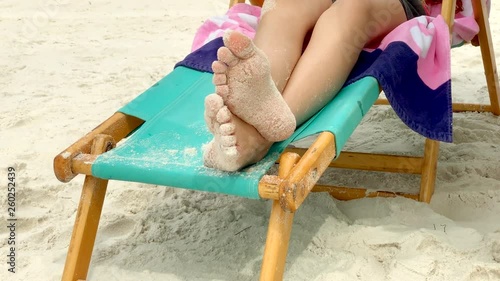 closeup of a girl's sandy feet relaxing in a beach chair on the beach photo