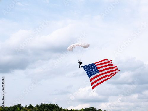 presentation of colors by skydiver carrying huge american flag at sporting event in the united states of amaerica photo