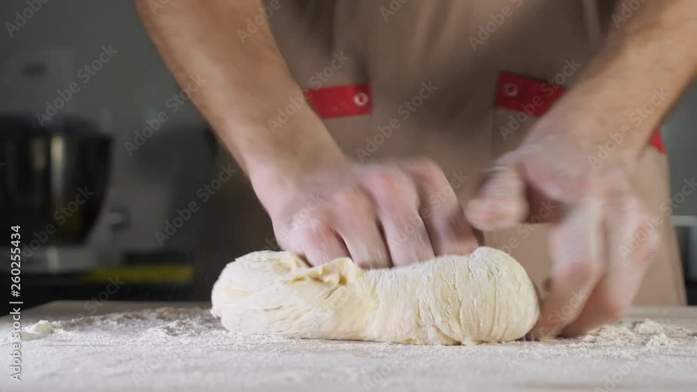 Chef baker is kneading dough with flour by hands on the table. Hands close-up. Chef baker is kneading dough with flour by hands on the table. Hands close-up.