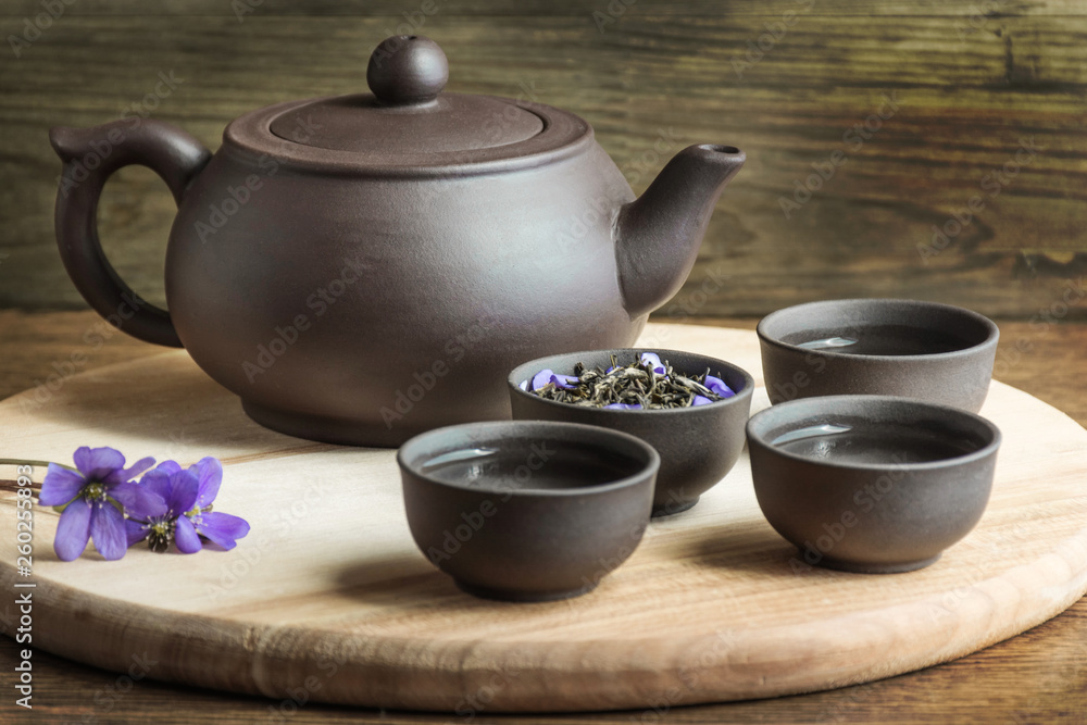 Set for tea ceremony. Large clay teapot, fresh green tea and cups on wooden background. Front view. Copy space, space for text, isolated. Set for tea ceremony. Large clay teapot, fresh green tea and cups on wooden background. Front view. Copy space, space for text, isolated.