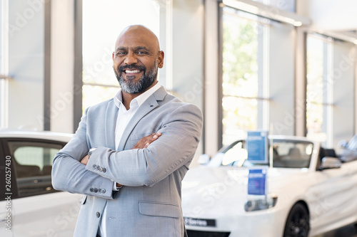 Happy salesman in car showroom