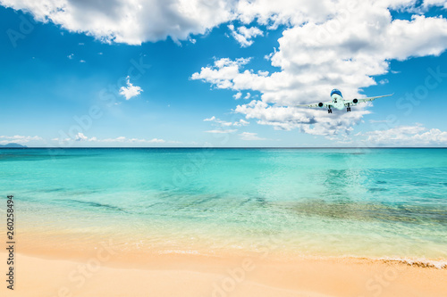 Fototapeta Naklejka Na Ścianę i Meble -  Airliner in the distance above the beautiful Caribbean ocean, will land at Maho beach of Sint Maarten.