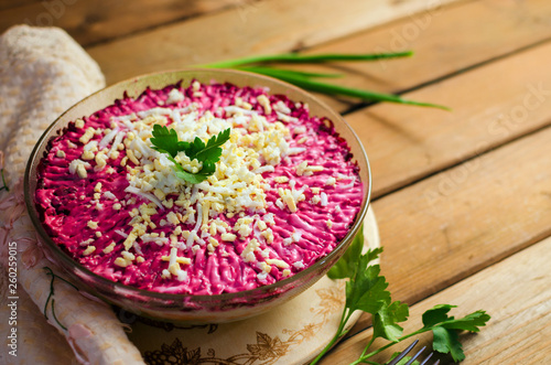 Foto Traditional Russian herring under a fur coat on a white plate with parsley