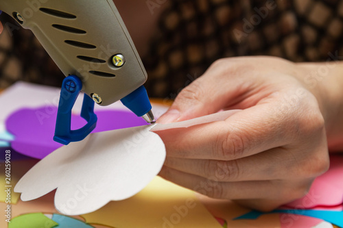 Woman uses hot melt glue gun in handmade applications. Closeup, selective focus