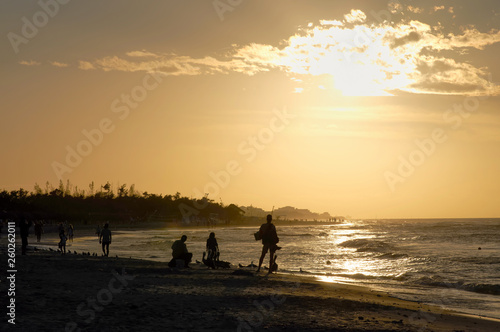 Evening beach at sunset with dark figures of fishermen toning