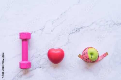 I love healthy food concept, flat lay of pink dumbbell with red heart and green apple on white marble background