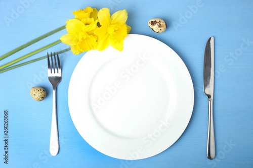 Empty plate  cutlery  quail eggs and narcissus.