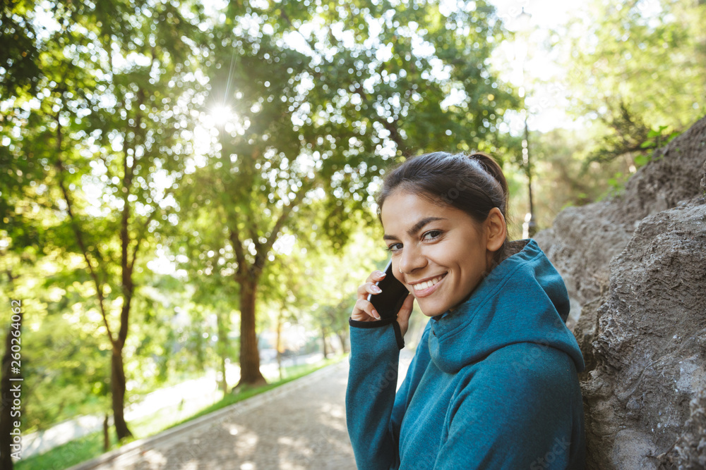 Smiling sportswoman talking on mobile phone Smiling sportswoman talking on mobile phone