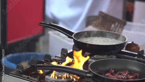 Frying pan on fire, chef Frying vegetables on fire throwing them in a frying pan.