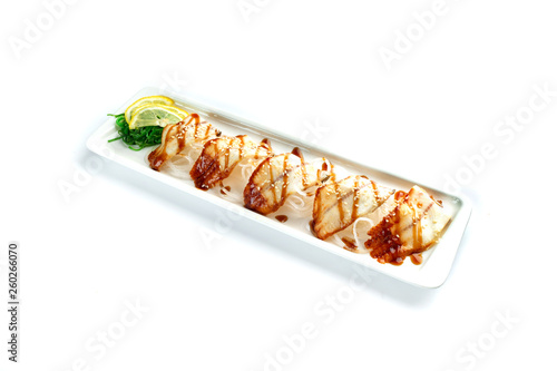 pieces of white fish with lemon and herbs on a rectangular plate on an isolated white background