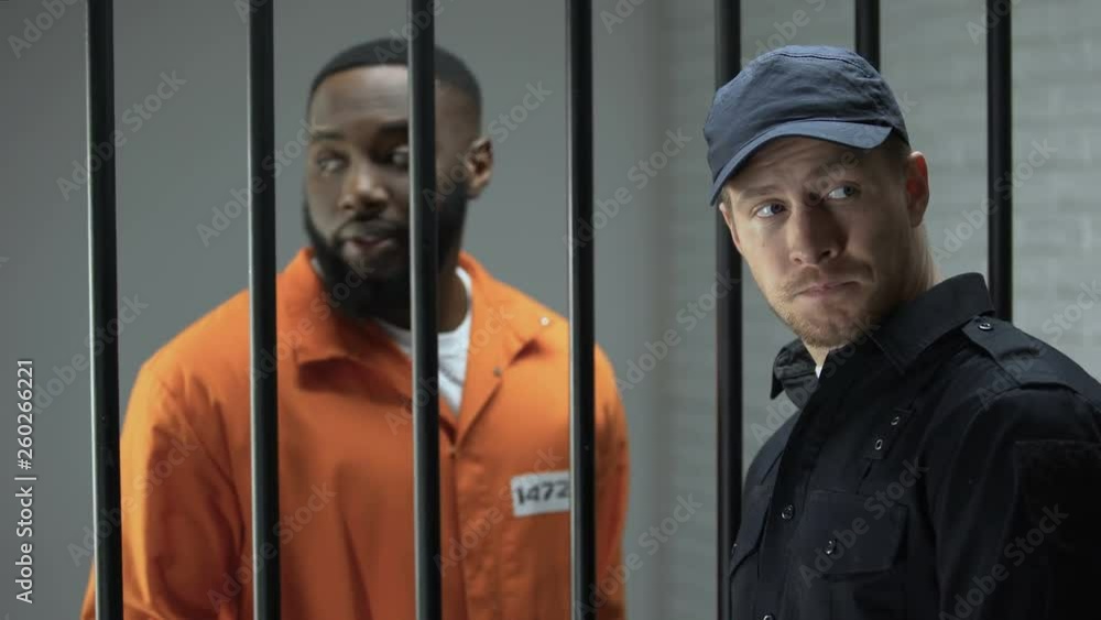 Jail guard giving african-american prisoner packet with pills, illegal activity Jail guard giving african-american prisoner packet with pills, illegal activity