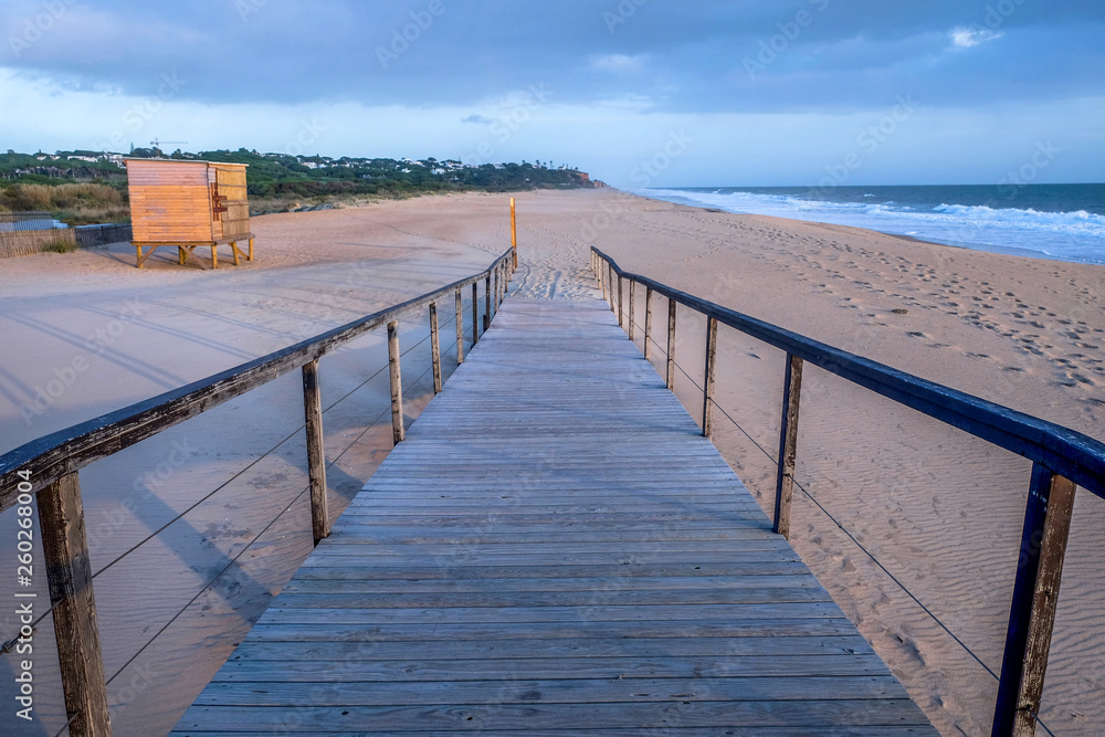 looking down a wooden decking pathway on a beach