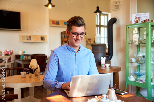 Young coffee shop owner businessman working on his laptop