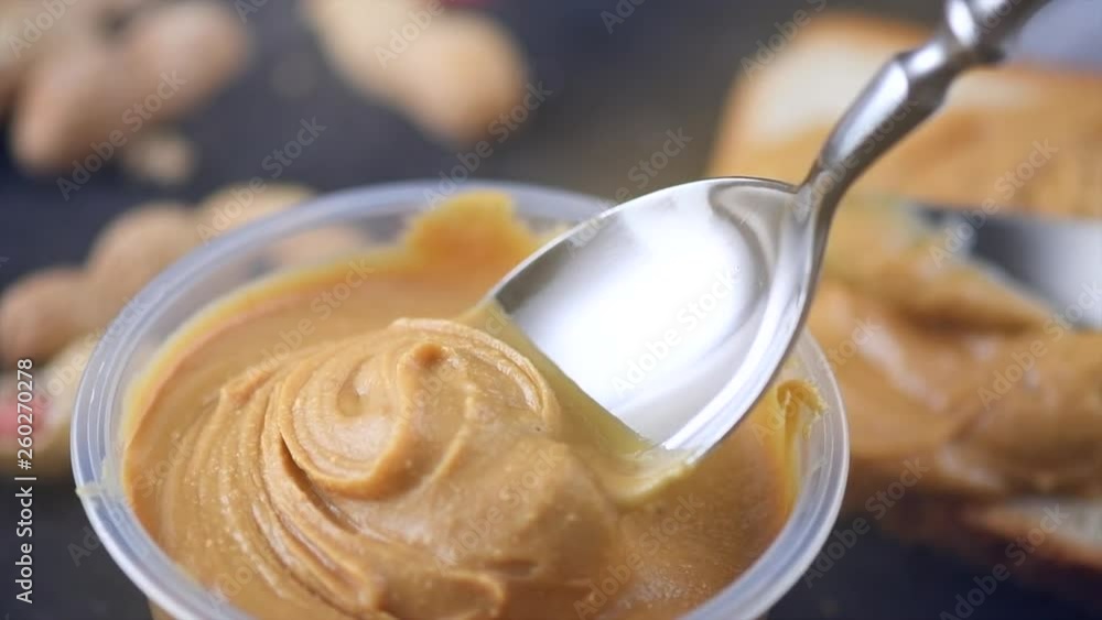 Peanut butter. Creamy smooth peanut butter in jar on a table. Spoon on Natural nutrition and organic food. American cuisine. 4K UHD video, slow motion Peanut butter. Creamy smooth peanut butter in jar on a table. Spoon on Natural nutrition and organic food. American cuisine. 4K UHD video, slow motion