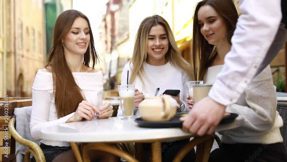 Group of young female friends hanging out in the city. Multiracial young women sitting by the street and having fun Group of young female friends hanging out in the city. Multiracial young women sitting by the street and having fun
