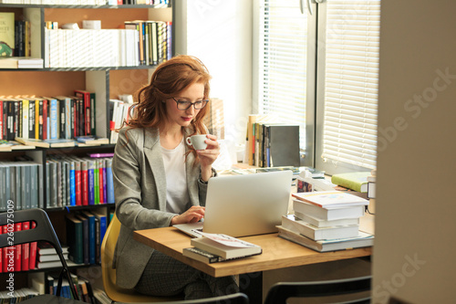 Vászonkép In her office, a dedicated female professor meticulously inspects tests, reviewing each student's progress with care and dedication, ensuring a fair and thorough evaluation process