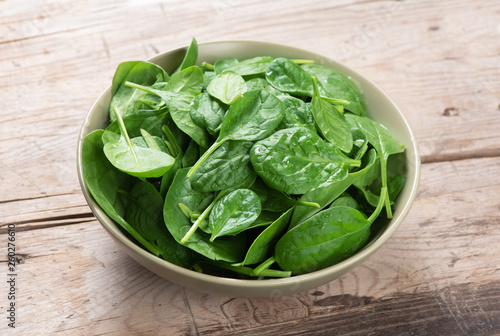 fresh green spinach in a bowl on wooden table
