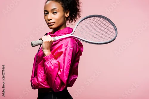 Obraz piękna sportsmenka Afroamerykanów, patrząc na kamery, podczas gdy pozowanie z rakieta tenisowa na różowo
